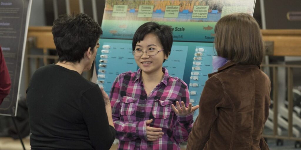 Student presenting their poster to two people