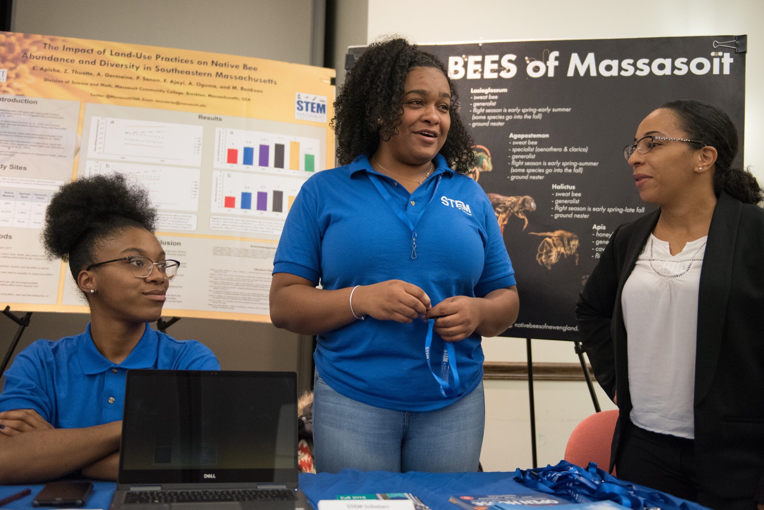 Two interns discuss their research with a colleague